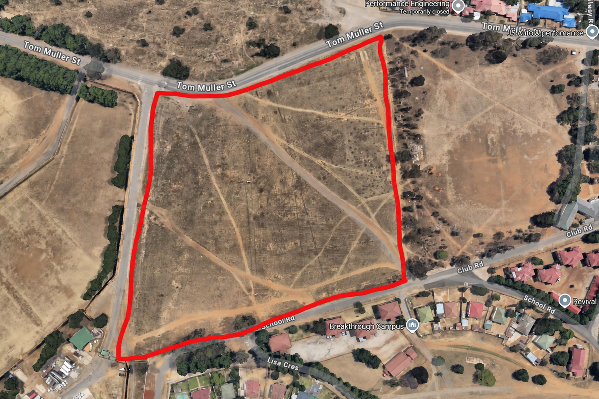 Aerial view of a large, vacant residential plot with prominent road frontage, suitable for future development.