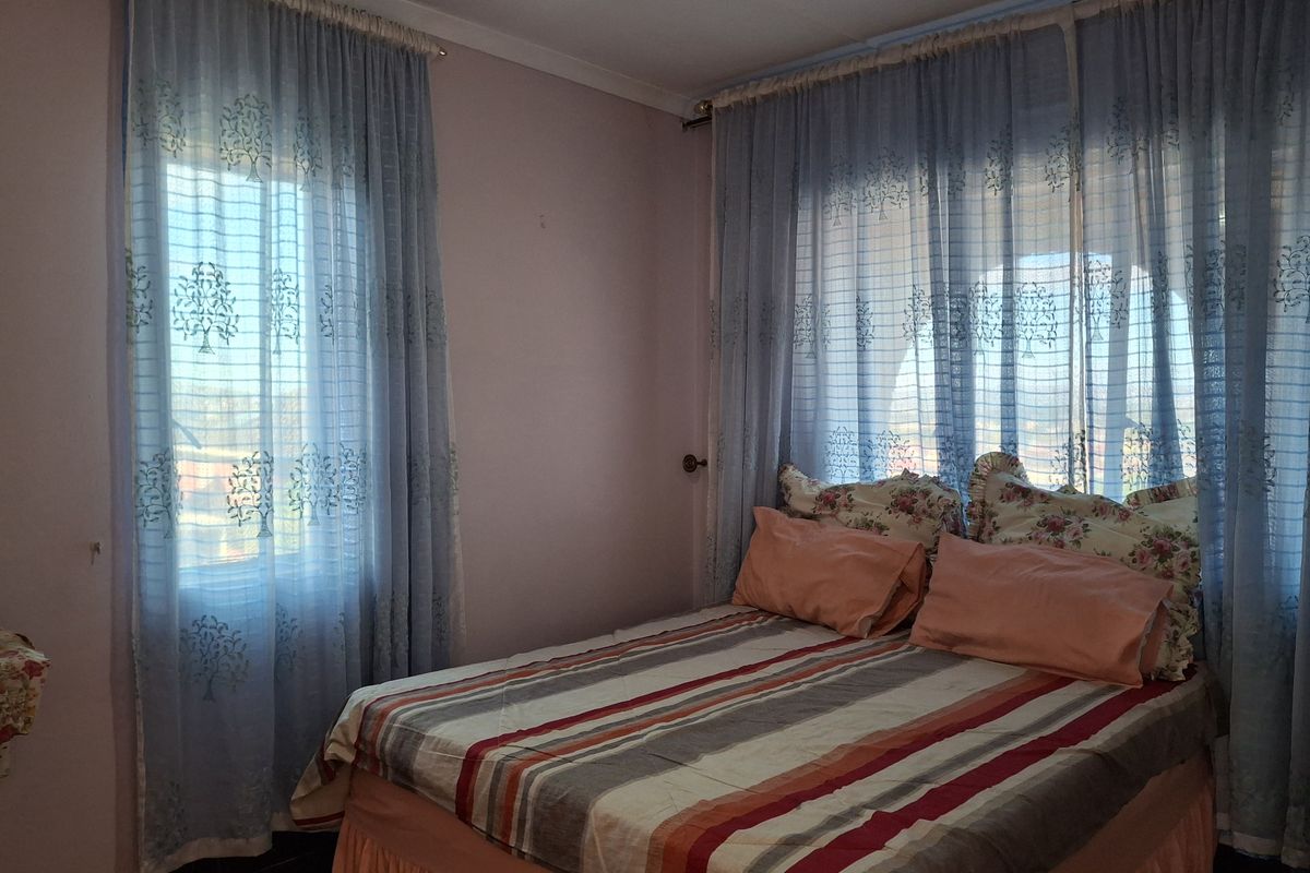 A bedroom featuring dual aspect windows with sheer curtains, providing natural light and views.