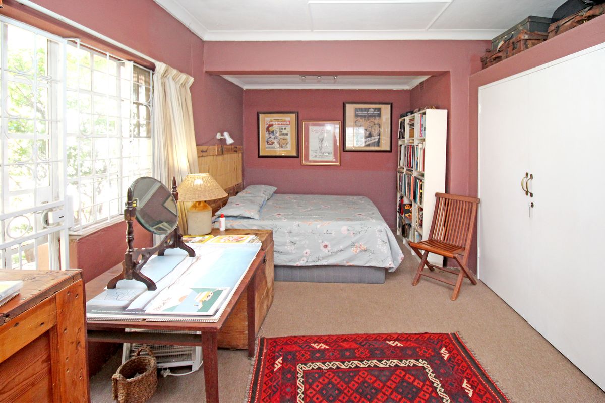 A bedroom featuring built-in wardrobe storage, security bars on the window, and neutral carpeting.