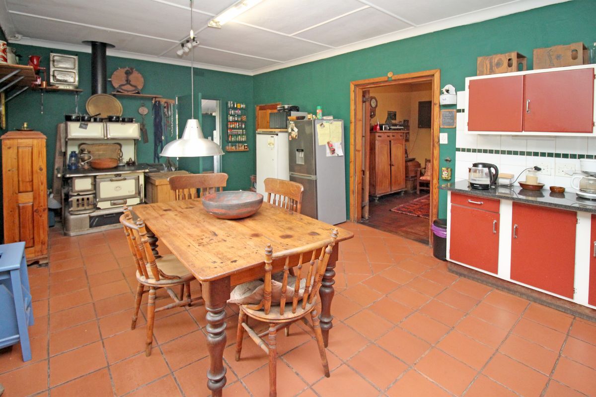 Spacious farmhouse kitchen featuring a vintage cast iron stove, tiled flooring, and functional cabinetry with granite countertops, offering a rustic and traditional aesthetic.