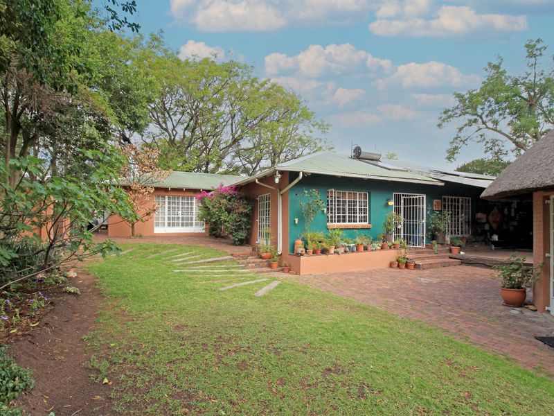 Rear view of the farm property featuring a brick paved patio, metal roofing with solar water heater, and established garden surroundings.