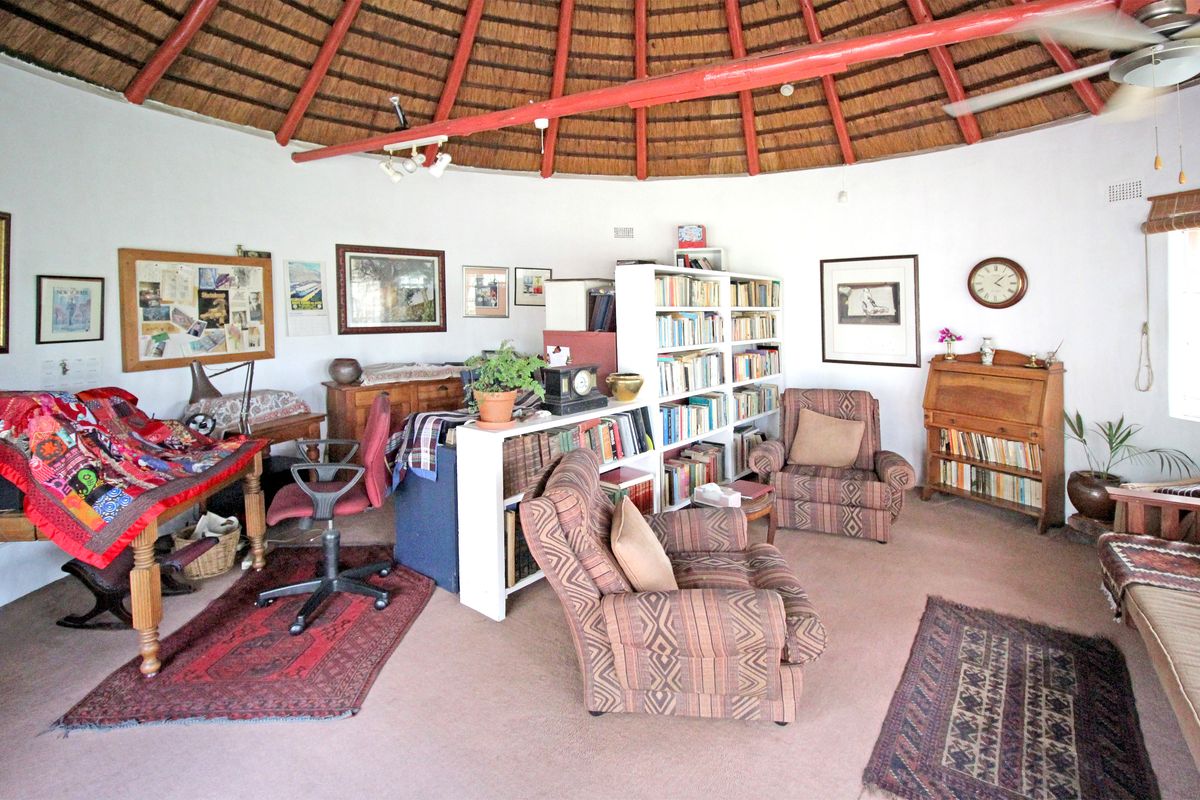 A circular living area featuring a traditional exposed thatch roof with timber rafters and a ceiling fan, providing a unique rustic architectural character.
