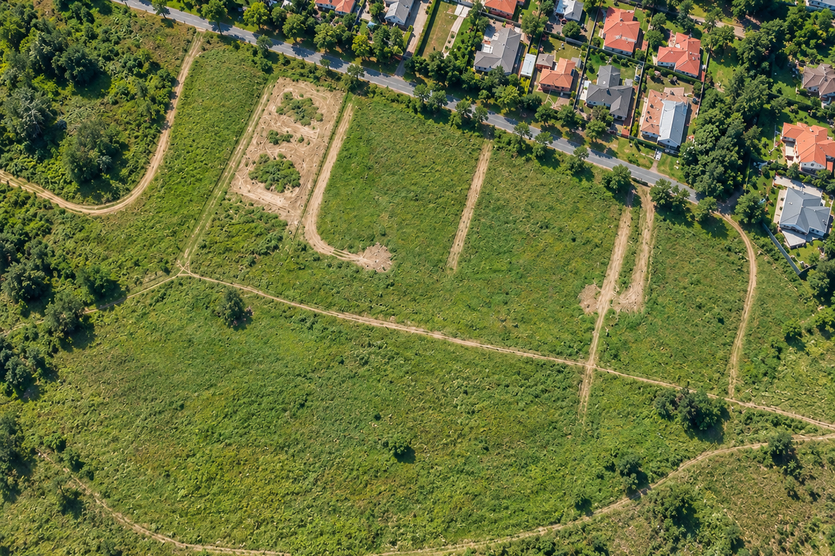 Aerial view of a large, undeveloped residential land parcel featuring natural vegetation and existing dirt access tracks.