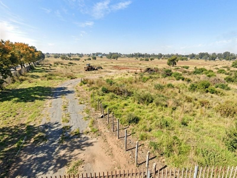 An aerial view of a large, undeveloped residential land parcel featuring perimeter fencing and an unpaved access road.