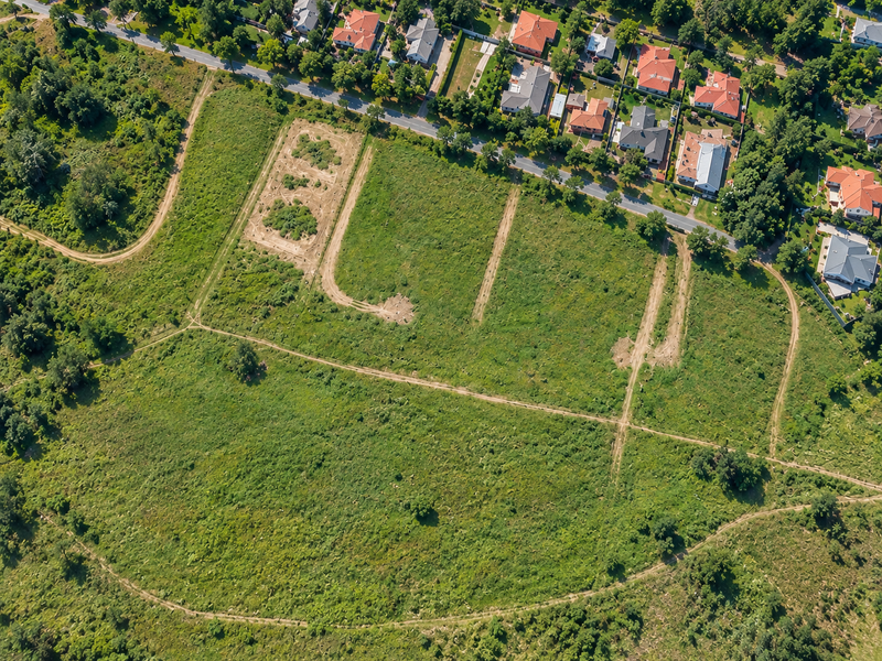 Aerial view of a large, undeveloped residential land parcel featuring natural vegetation and existing dirt access tracks.