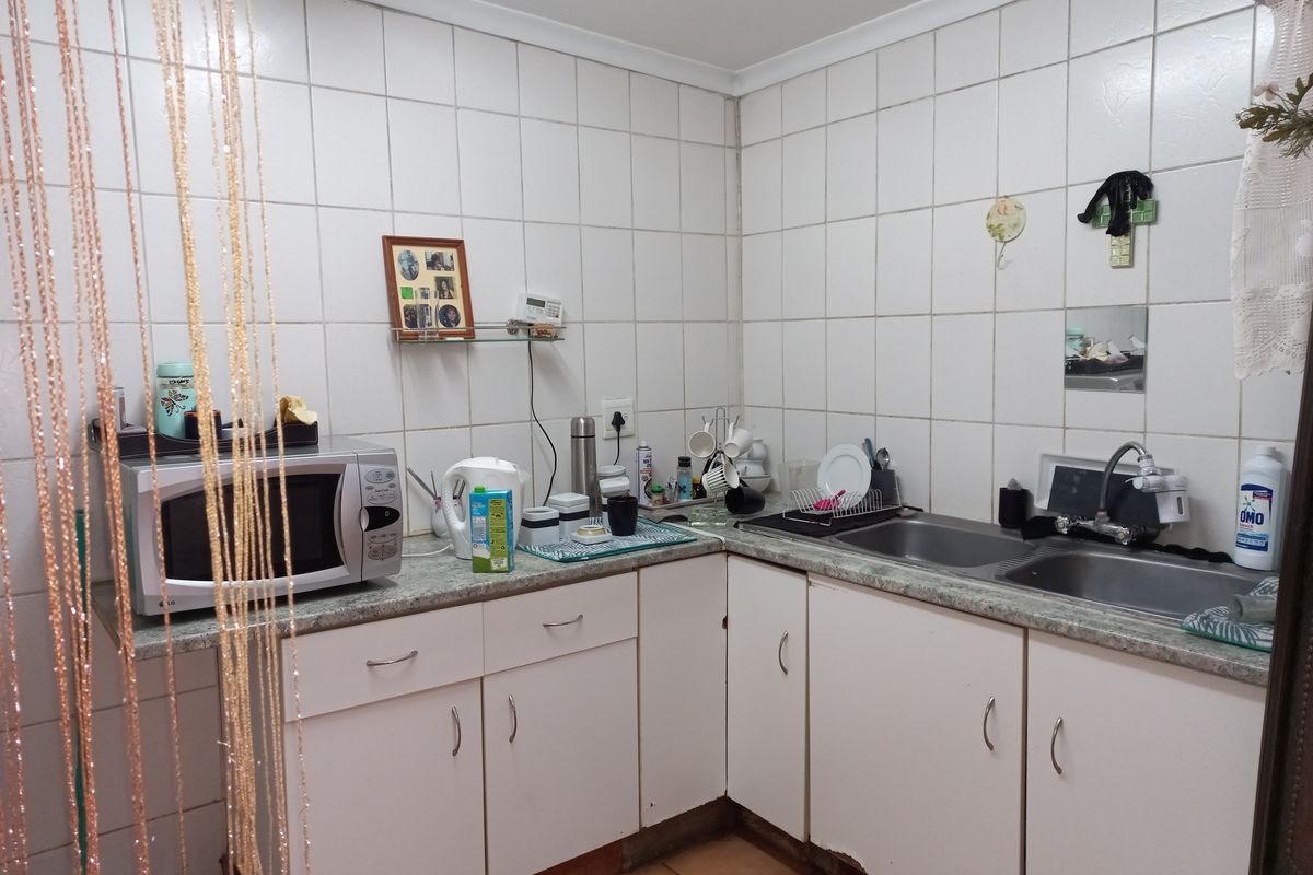 A functional kitchen featuring white cabinetry, laminate countertops, and a double bowl stainless steel sink with tiled splashback.