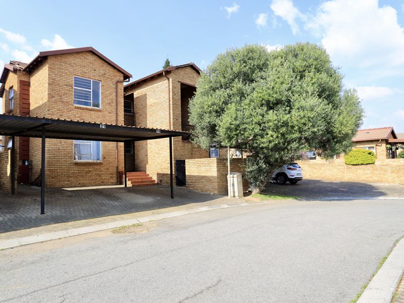 Exterior view of a face brick apartment complex featuring a covered carport and paved driveway area.