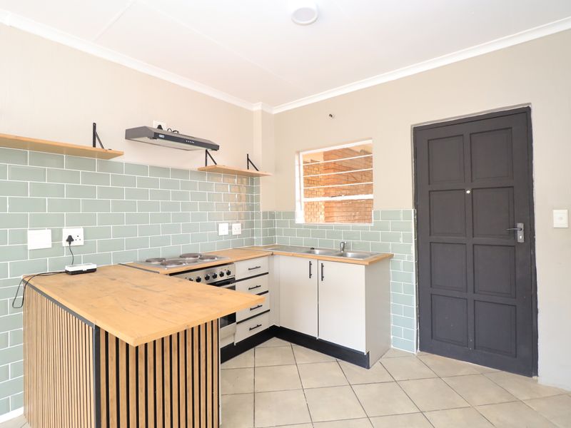 A clean, modern kitchen featuring a subway tile backsplash, wooden countertops, built-in oven with hob, and ample base cabinetry.
