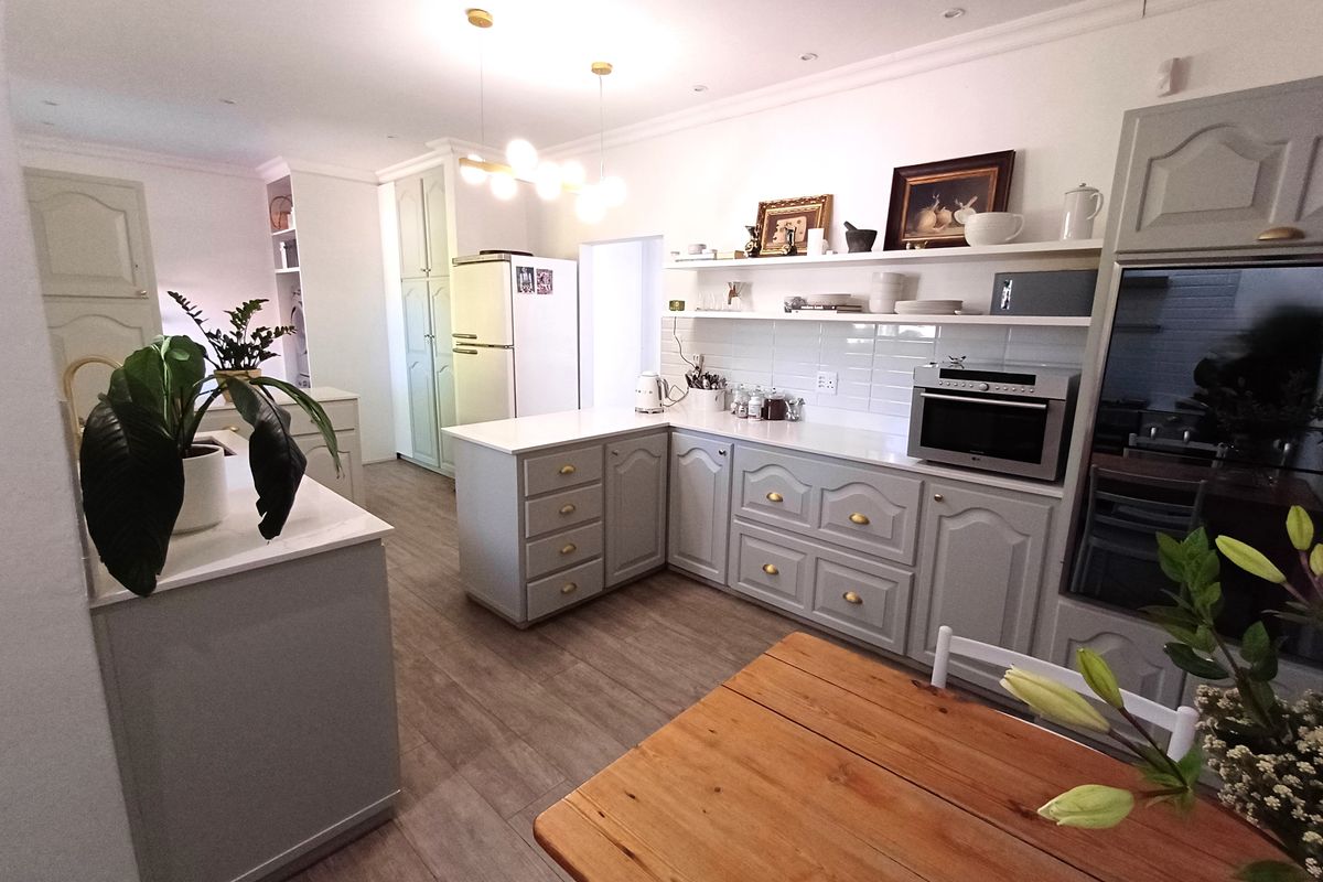 A well-maintained kitchen featuring light grey cabinetry, stone countertops, subway tile backsplash, and integrated shelving with modern recessed lighting.