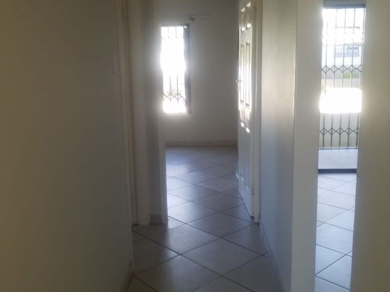 A functional hallway with tiled flooring providing access to adjacent rooms, featuring security gates and neutral wall finishes.