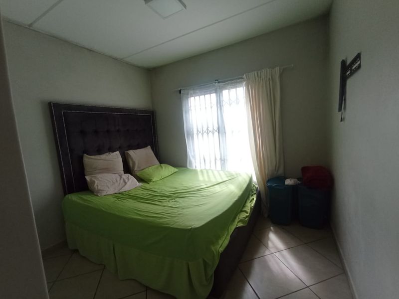 A standard bedroom featuring tiled flooring and a window fitted with a security gate.