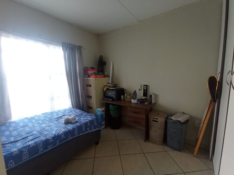 A functional bedroom featuring tiled flooring and a built-in wardrobe, offering a practical space with natural light from the window.