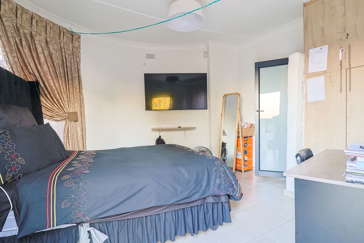 A bedroom featuring tiled flooring, built-in cupboards, and a glass panel door leading to an outdoor area.