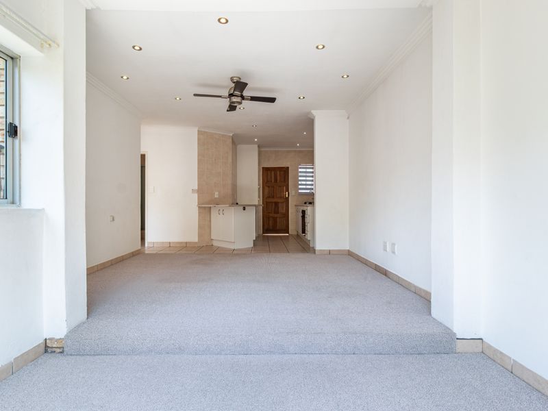 Spacious open-plan living and kitchen area featuring a split-level layout, recessed lighting, ceiling fan, and neutral finishes throughout.