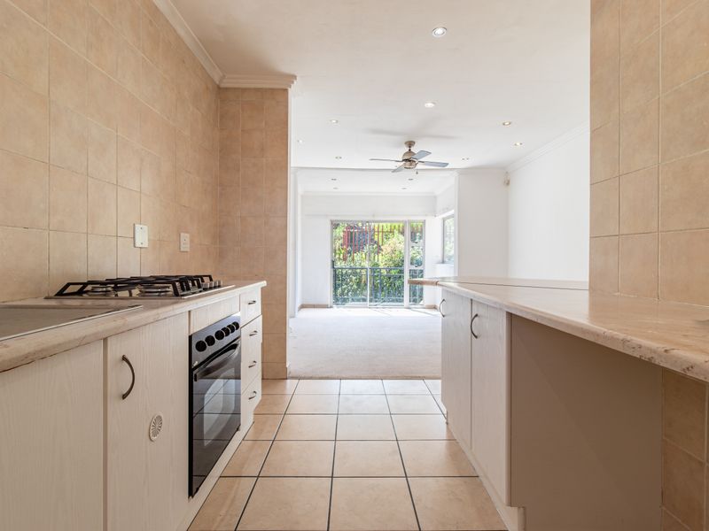 Open plan kitchen and living area featuring tiled flooring, stone countertops, built-in oven, gas hob, and sliding glass doors leading to an outdoor space.