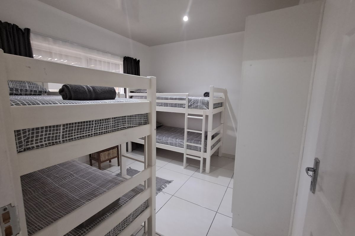 A functional bedroom featuring tiled flooring, recessed downlighting, and a built-in cupboard, currently configured with bunk beds.