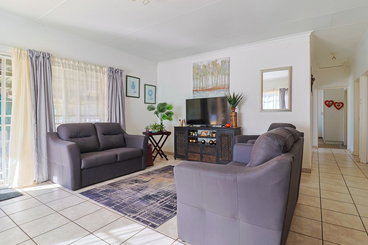 A bright and spacious living room featuring neutral tiled flooring, a coved ceiling, and a sliding glass door providing access to the exterior.