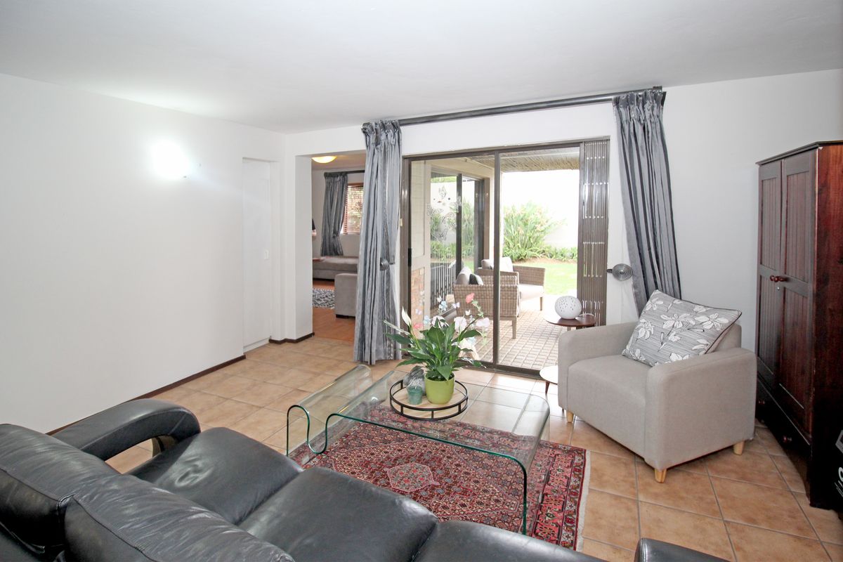 A bright living room featuring tiled flooring and large sliding glass doors that provide direct access to an outdoor patio area.