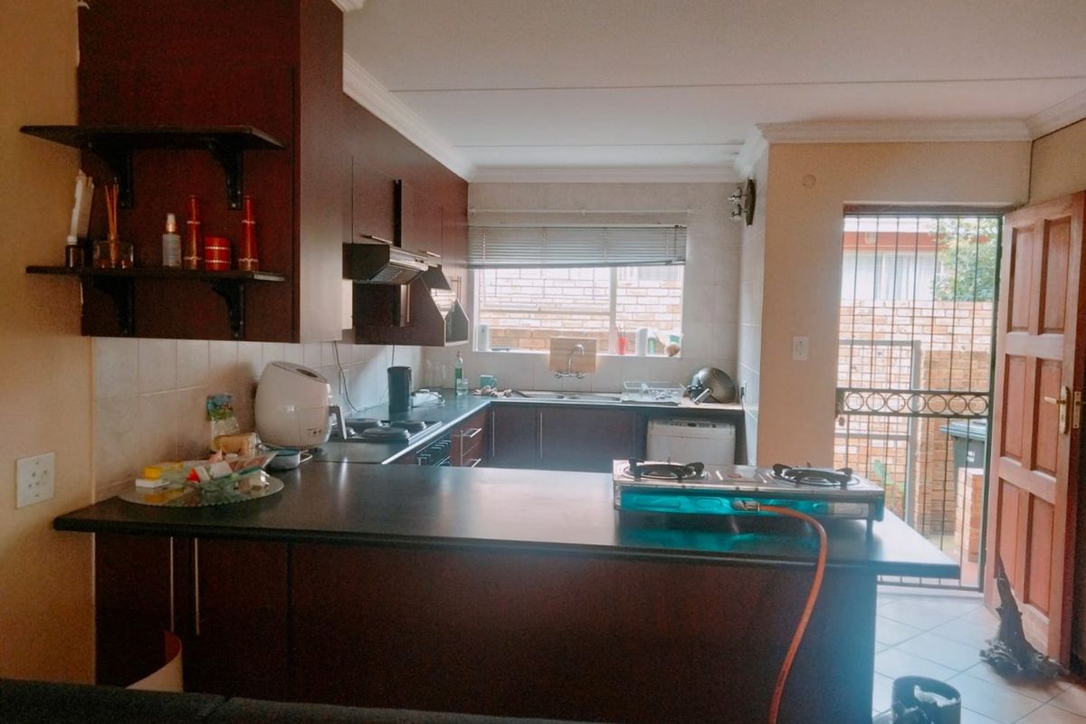 Functional kitchen featuring dark wood cabinetry, laminate countertops, and direct access to an outdoor area through a security gate.