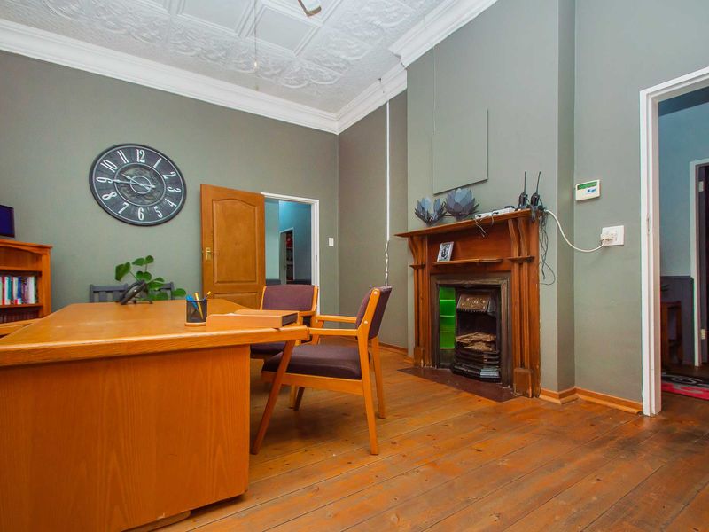 A home office featuring original timber flooring, an ornate pressed metal ceiling, and a classic timber fireplace mantel with a cast iron insert.