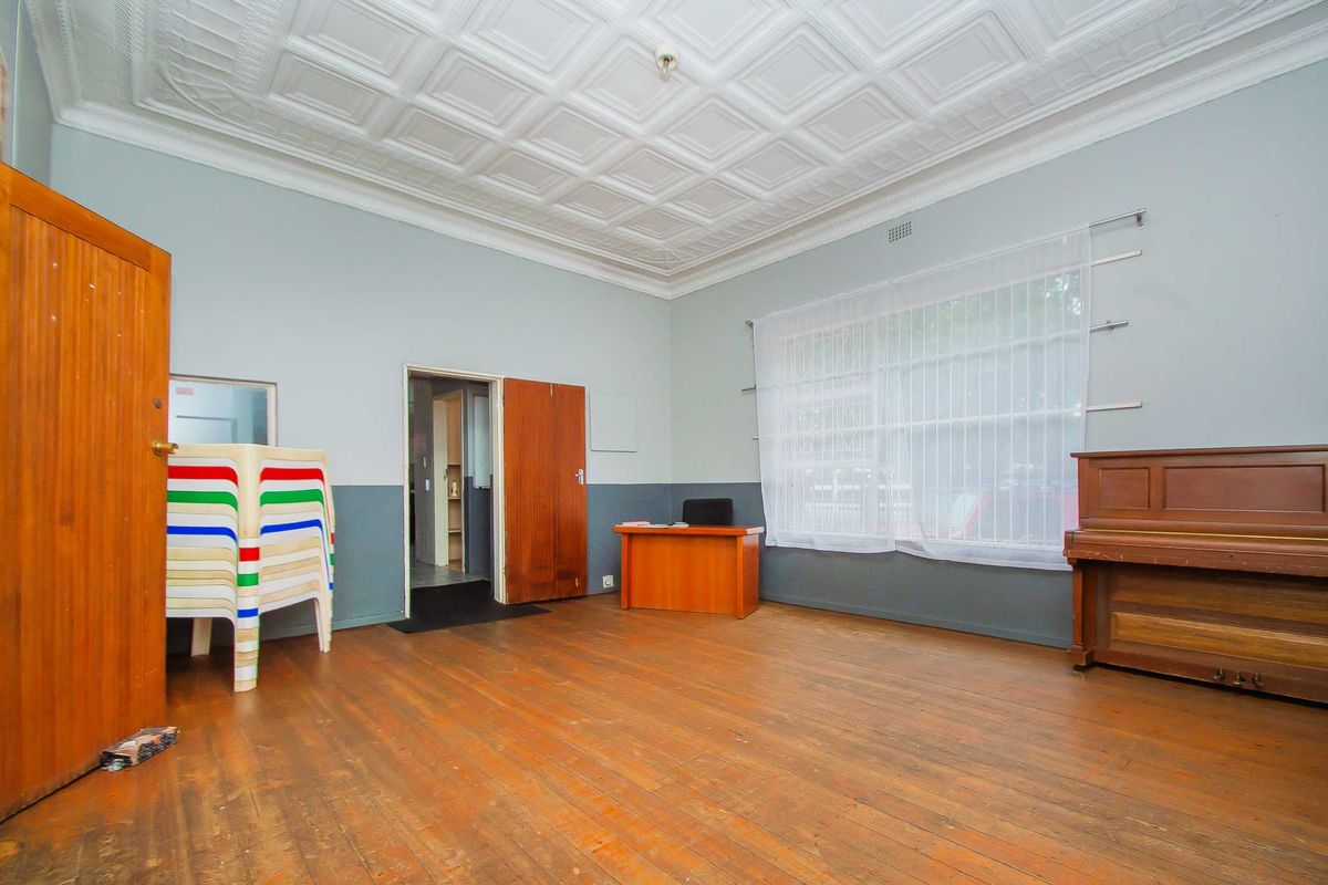 Spacious living area featuring original pressed metal ceilings, polished timber flooring, and large windows providing ample natural light.