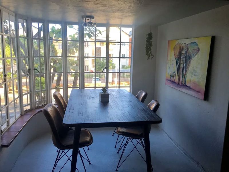 A dining area featuring a large bay window that provides ample natural light and views of the surrounding complex.