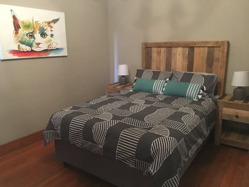 A cozy bedroom featuring warm hardwood flooring and neutral wall tones, providing a comfortable and inviting sleeping space.