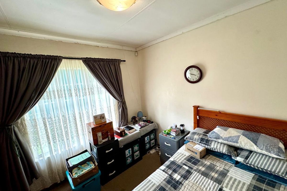 A standard bedroom featuring carpeted flooring, a large window with curtain tracks, and a ceiling-mounted light fixture.