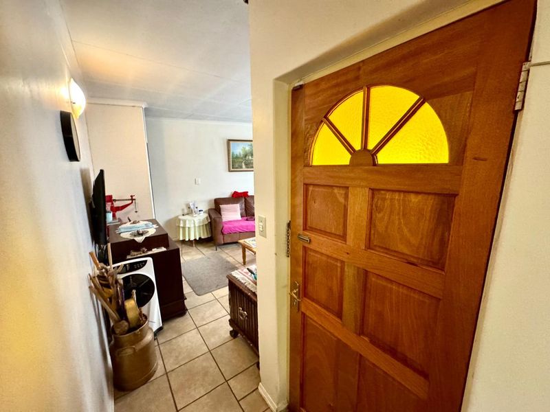 An entry hallway featuring tiled flooring and a solid timber front door with a decorative yellow glass insert, leading into the main living area.