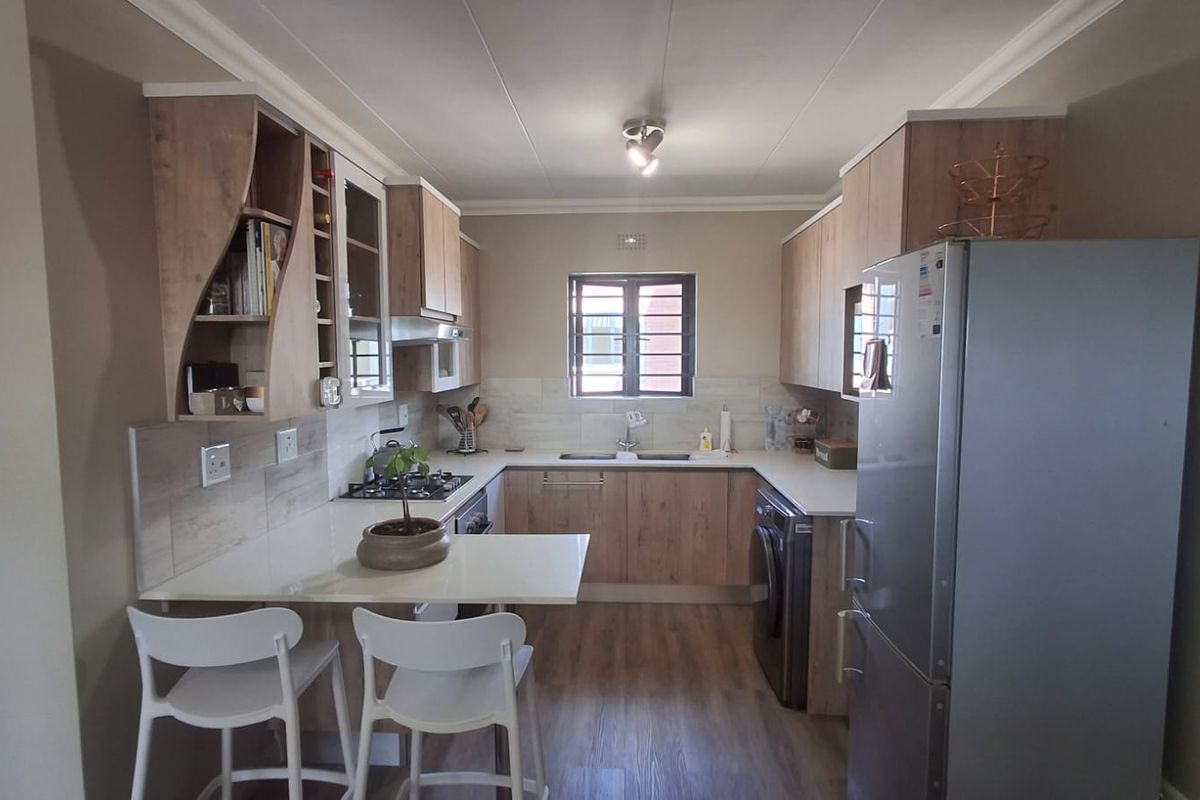 Modern kitchen featuring light wood-finish cabinetry, laminate countertops, a breakfast nook, and integrated gas hob with tiled backsplash.