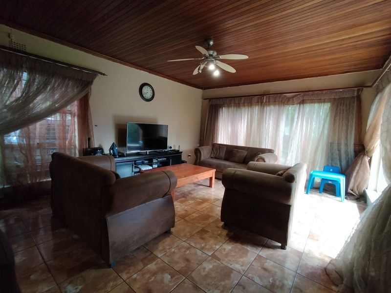 A living room featuring a timber ceiling with a central ceiling fan and tiled flooring throughout.
