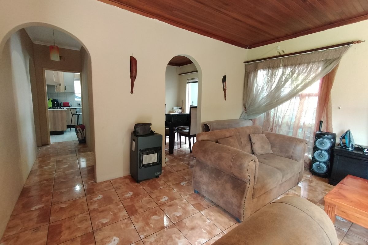 Living room featuring ceramic floor tiles, arched architectural transitions, and a timber tongue and groove ceiling, providing a traditional layout with access to adjacent rooms.