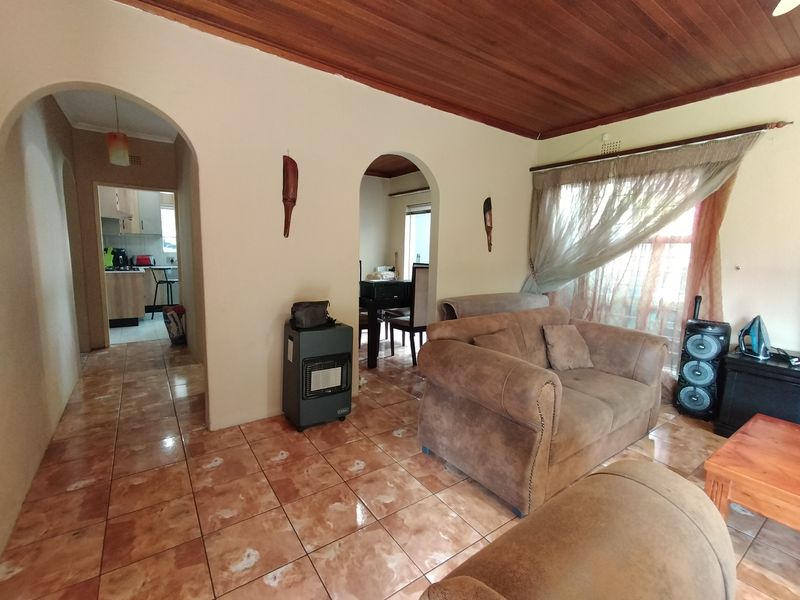 Living room featuring ceramic floor tiles, arched architectural transitions, and a timber tongue and groove ceiling, providing a traditional layout with access to adjacent rooms.