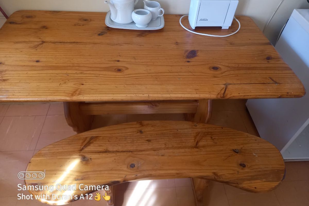 A close-up view of a wooden table and bench set situated on tiled flooring, likely within a kitchen or dining area.