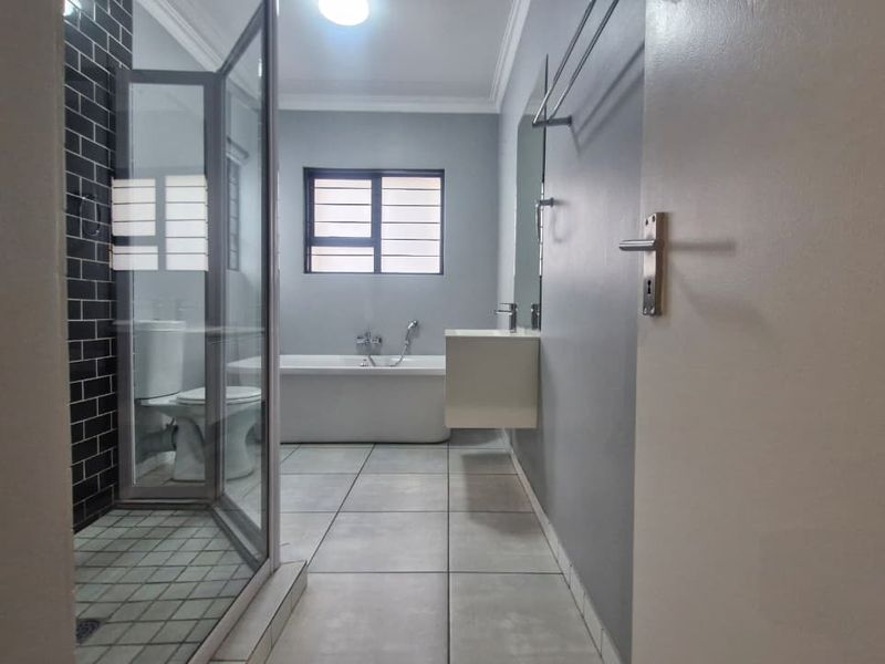 Modern bathroom featuring a freestanding bathtub, glass-enclosed shower with subway tile accents, and a wall-mounted vanity with clean, contemporary finishes.
