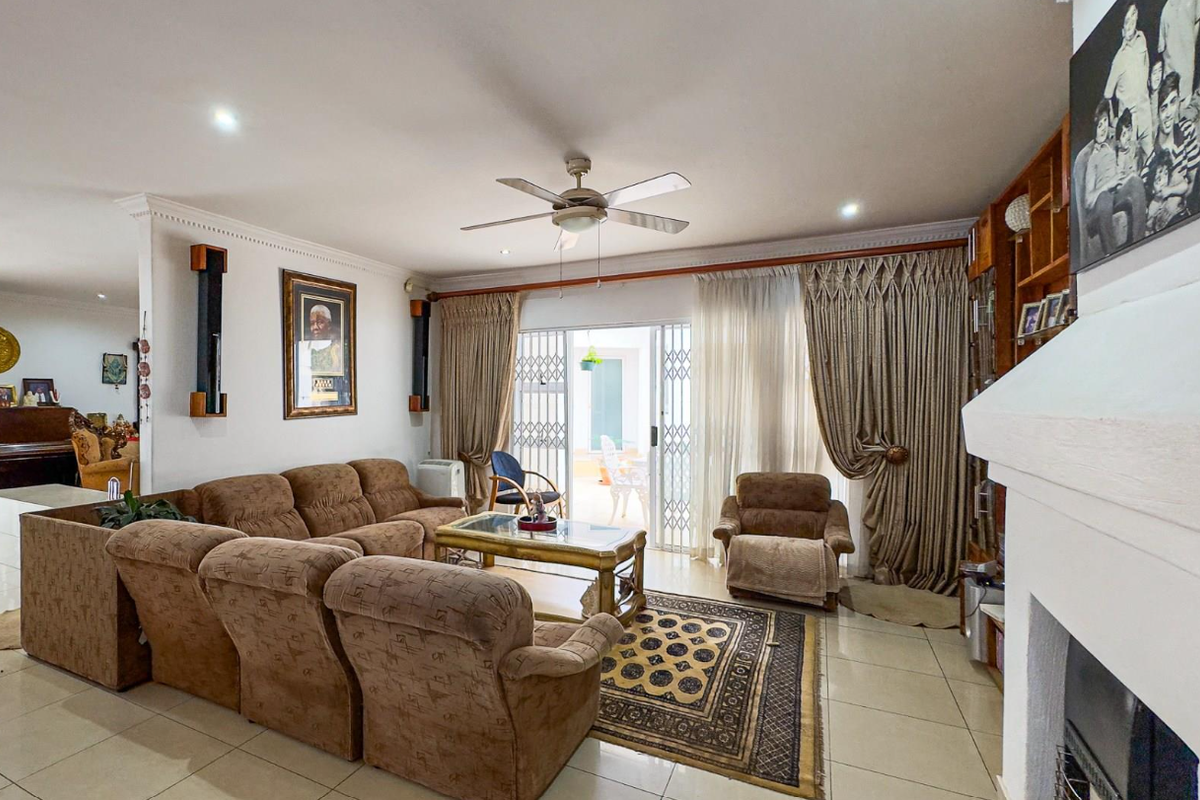 Spacious living room featuring tiled flooring, a ceiling fan, a fireplace, and direct access to the patio through sliding glass doors.