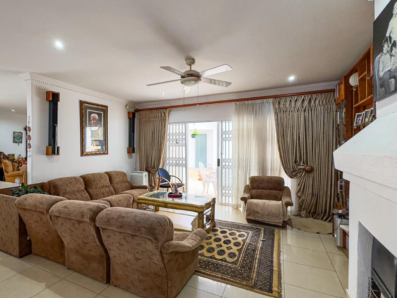 Spacious living room featuring tiled flooring, a ceiling fan, a fireplace, and direct access to the patio through sliding glass doors.