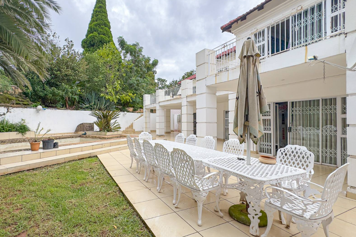 Spacious rear patio area featuring tiled flooring, direct garden access, and a raised garden bed, providing a functional outdoor entertainment space.