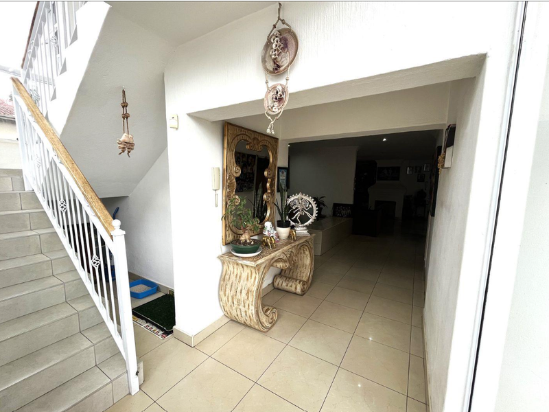 An entrance foyer featuring ceramic floor tiles and a staircase with a white metal balustrade and wooden handrail leading to the upper level.