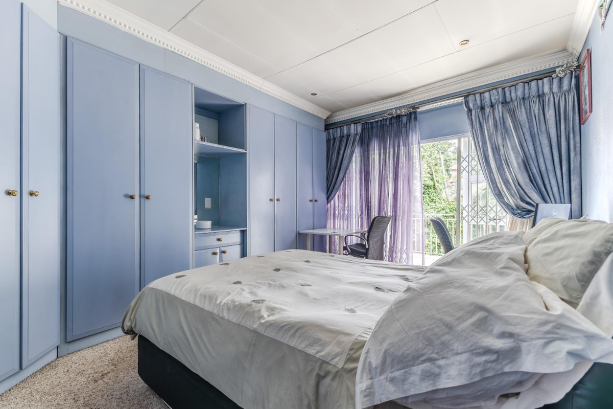 A bedroom featuring extensive built-in blue cabinetry, crown molding, and a sliding glass door providing access to an outdoor balcony area.