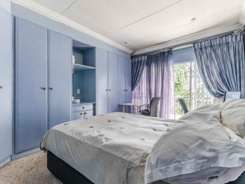 A bedroom featuring extensive built-in blue cabinetry, crown molding, and a sliding glass door providing access to an outdoor balcony area.