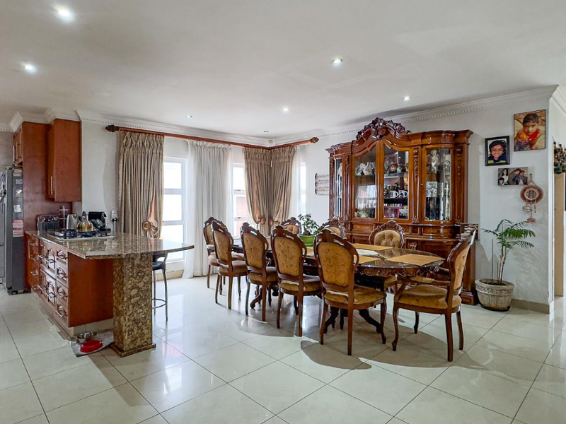 Spacious open-plan living and dining area featuring a granite-topped kitchen island, tiled flooring, and recessed lighting throughout.