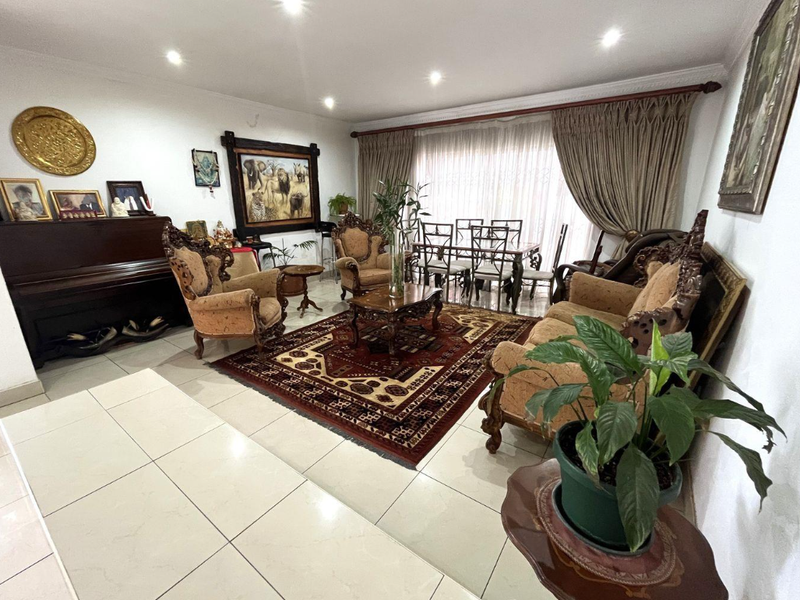 Spacious open-plan living and dining area featuring neutral tiled flooring, recessed downlighting, and large windows with curtain treatments.