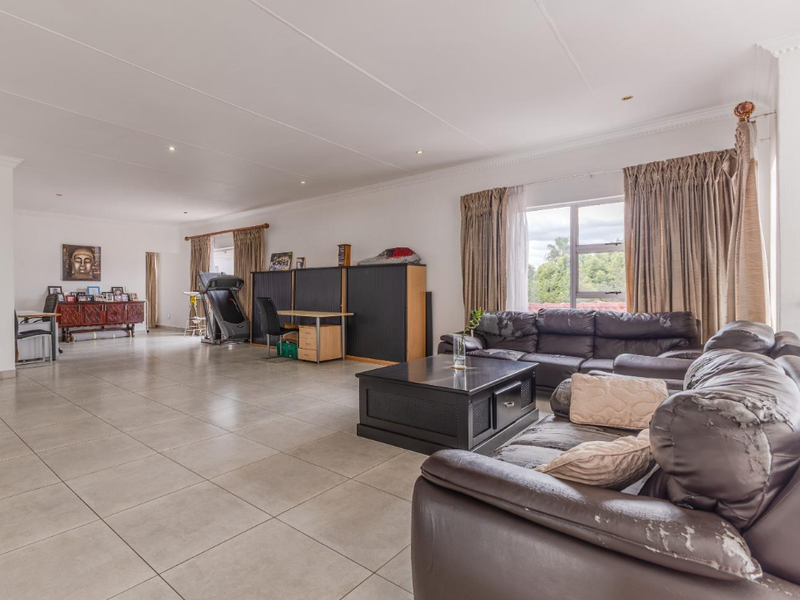 Spacious open-plan living area featuring large format floor tiles, recessed lighting, and decorative ceiling cornicing with ample natural light.