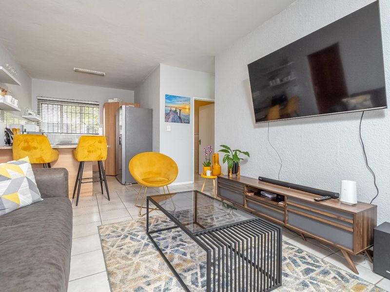 Open-plan living area featuring tiled flooring and a functional kitchen breakfast counter, creating a cohesive and versatile space for daily living.