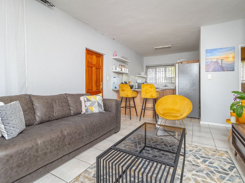 Open-plan living area featuring tiled flooring and a compact kitchen with built-in cabinetry and a breakfast counter.