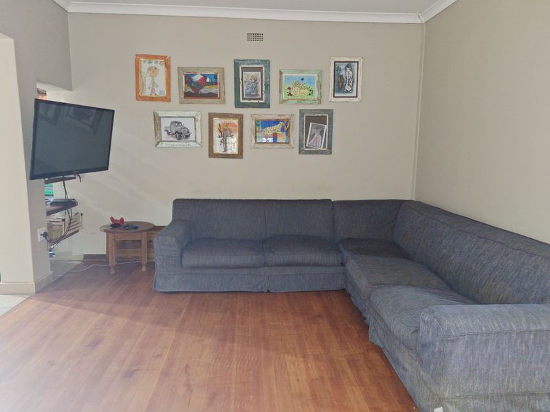 A comfortable living room featuring warm-toned laminate flooring and neutral wall finishes, providing a functional and inviting space for relaxation.