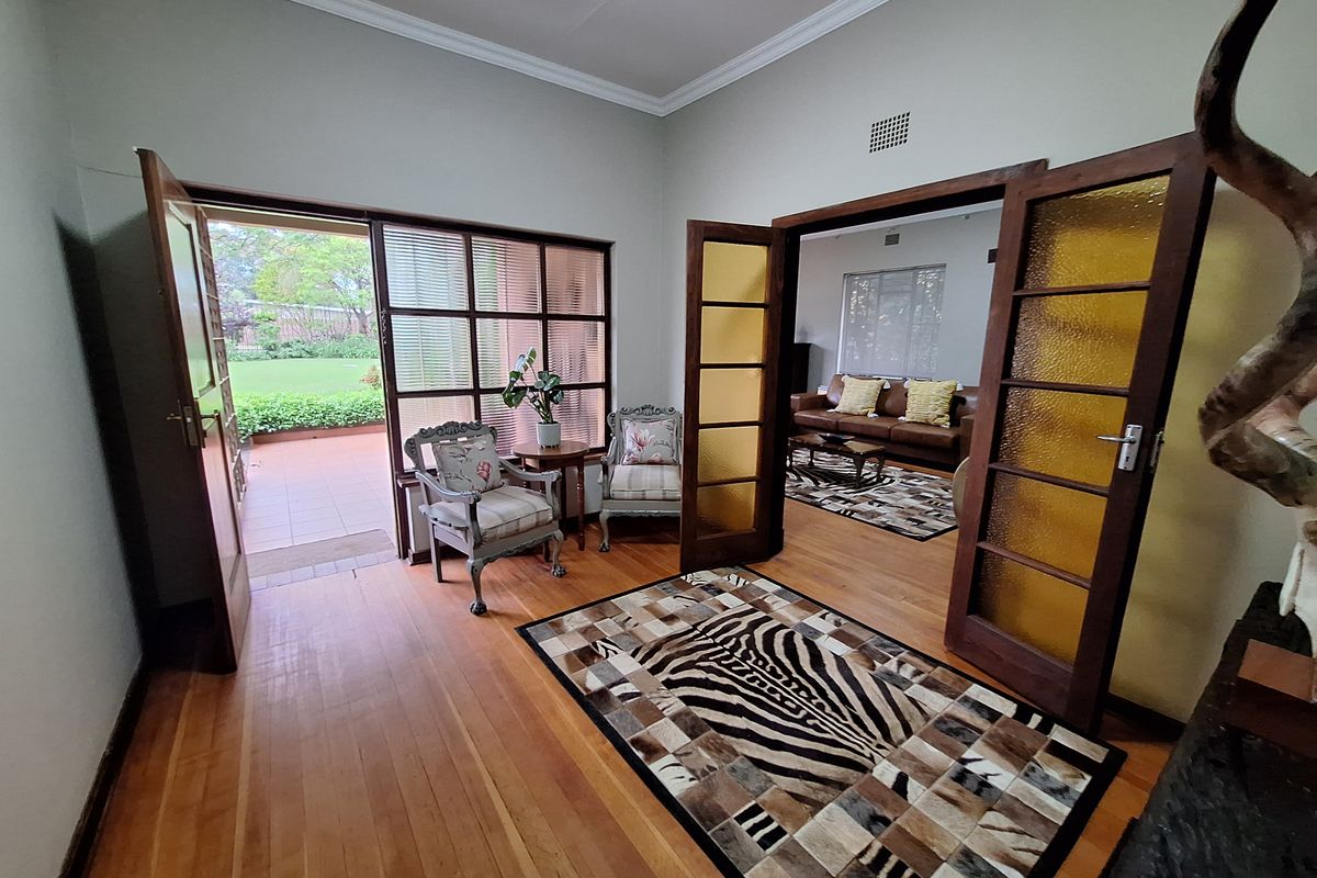 A bright living area featuring polished hardwood flooring, elegant crown molding, and classic timber-framed french doors providing direct access to the outdoor patio.