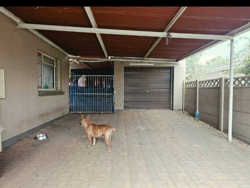Covered outdoor patio area featuring paved flooring, a corrugated metal roof, and direct access to a secure garage.
