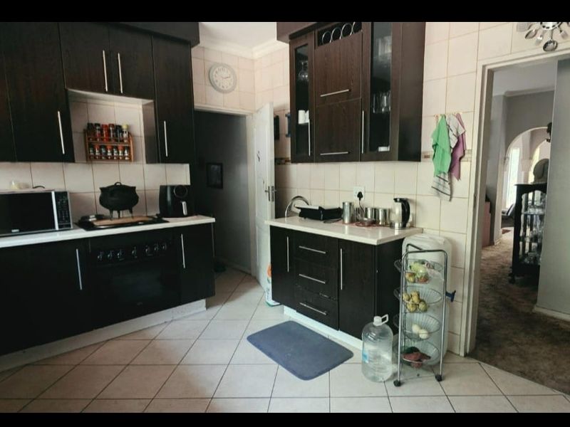 A functional kitchen featuring dark wood cabinetry, tiled backsplash, and tiled flooring, offering a practical layout with integrated cooking appliances.